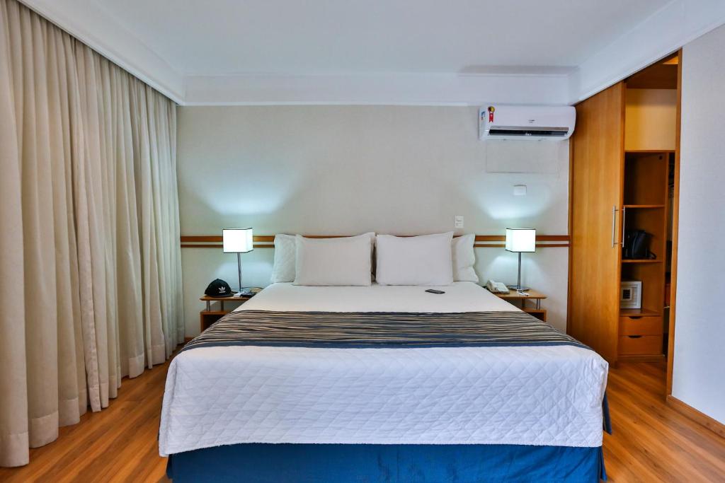 1 dormitorio con 1 cama grande y 2 lámparas en eSuites Sorocaba by Atlantica en Sorocaba