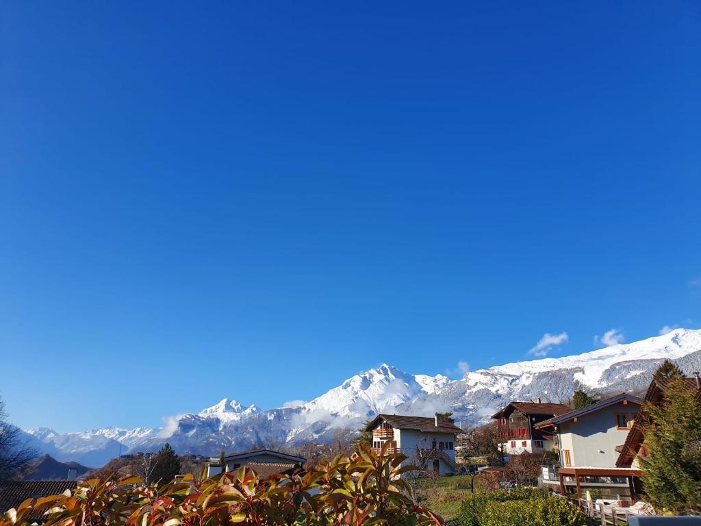 un pueblo con montañas cubiertas de nieve en el fondo en O Rendez Vous maison mitoyenne Piscine chauffée mars-octobre, en Grimisuat