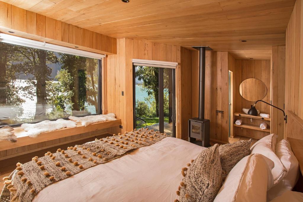 um quarto com uma cama grande e uma janela em Lodge Tagua Tagua, Puelo Patagonia em Puelo