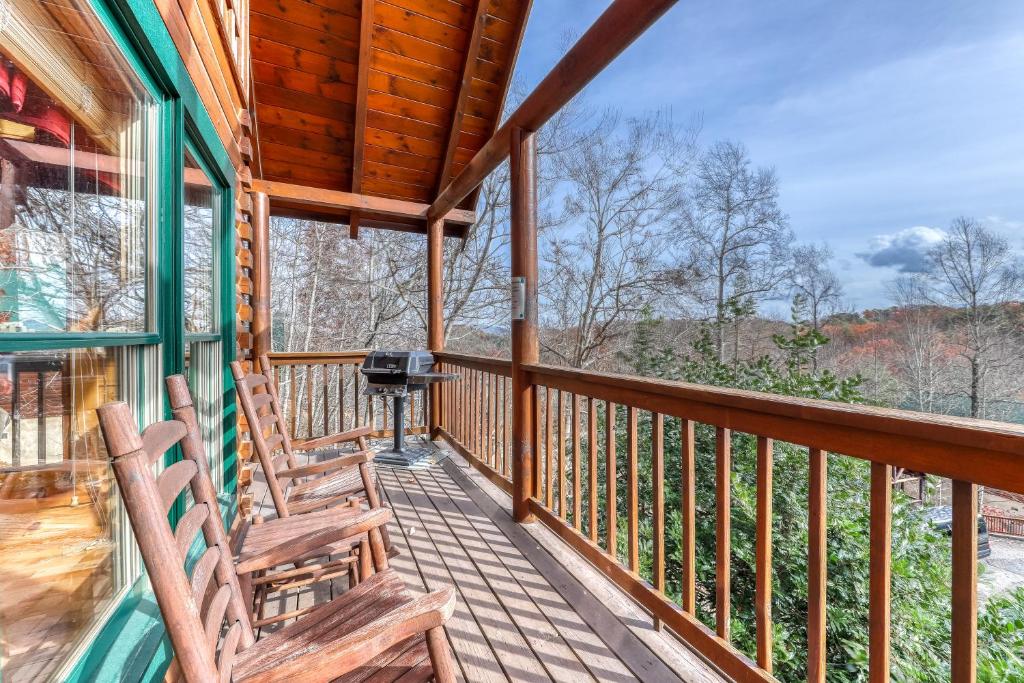 a porch of a cabin with chairs and a grill at Heavens Scent in Pigeon Forge