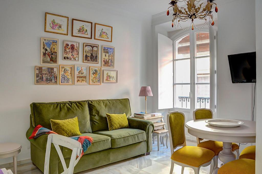 sala de estar con sofá verde y mesa en Apartamento Trajano, en Sevilla