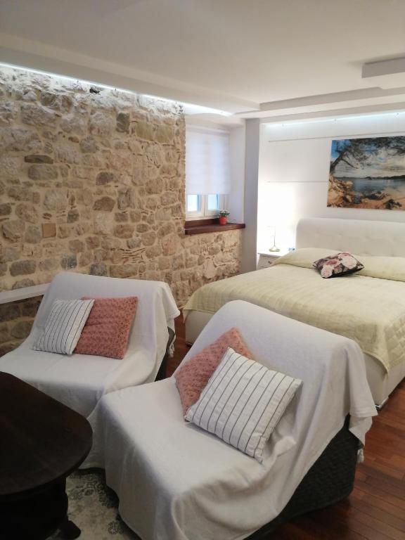 una camera con due letti e un muro di pietra di V&M Luxury Studio a Pag