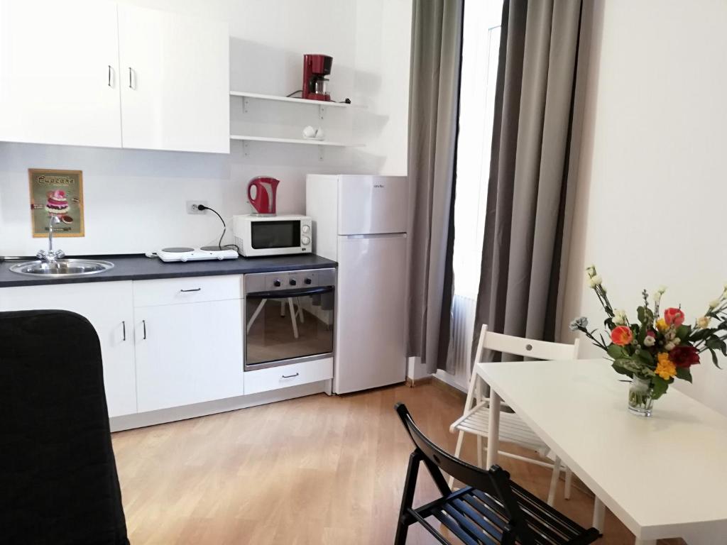 a white kitchen with a table and a white refrigerator at Studio Piata Amzei NR.1 (8 B) in Bucharest