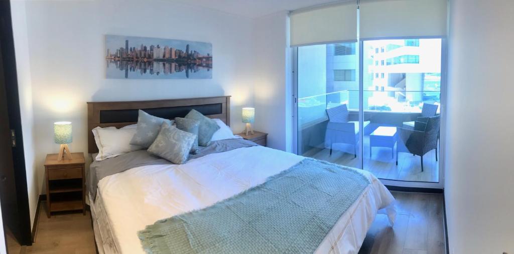une chambre avec un grand lit et un balcon dans l'établissement Acogedor Depto. a un costado de Clínica Las Condes, à Santiago