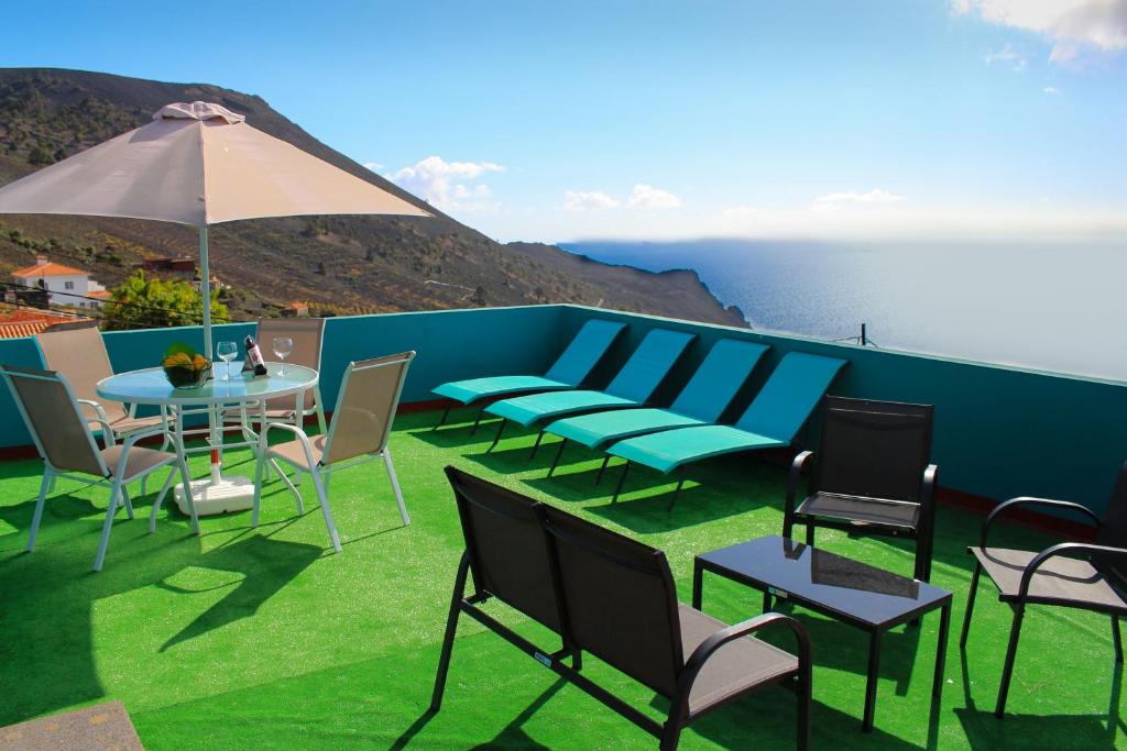 un patio con sillas, una mesa y una sombrilla en Surf House la Palma, en Fuencaliente de la Palma