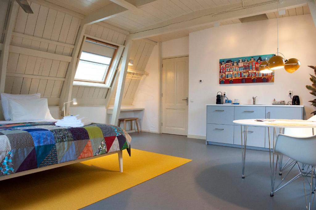 a bedroom with a bed and a table and a kitchen at BB88 in Leeuwarden