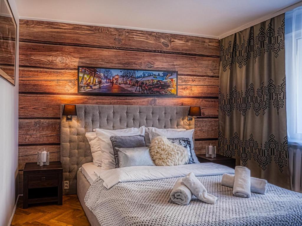 a bedroom with a wooden accent wall and a bed at Apartament Krupówki Center in Zakopane