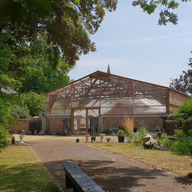 un grand bâtiment en verre avec un banc devant lui dans l'établissement LA POUDRIERE DE SAINT VENANT, à Saint-Venant