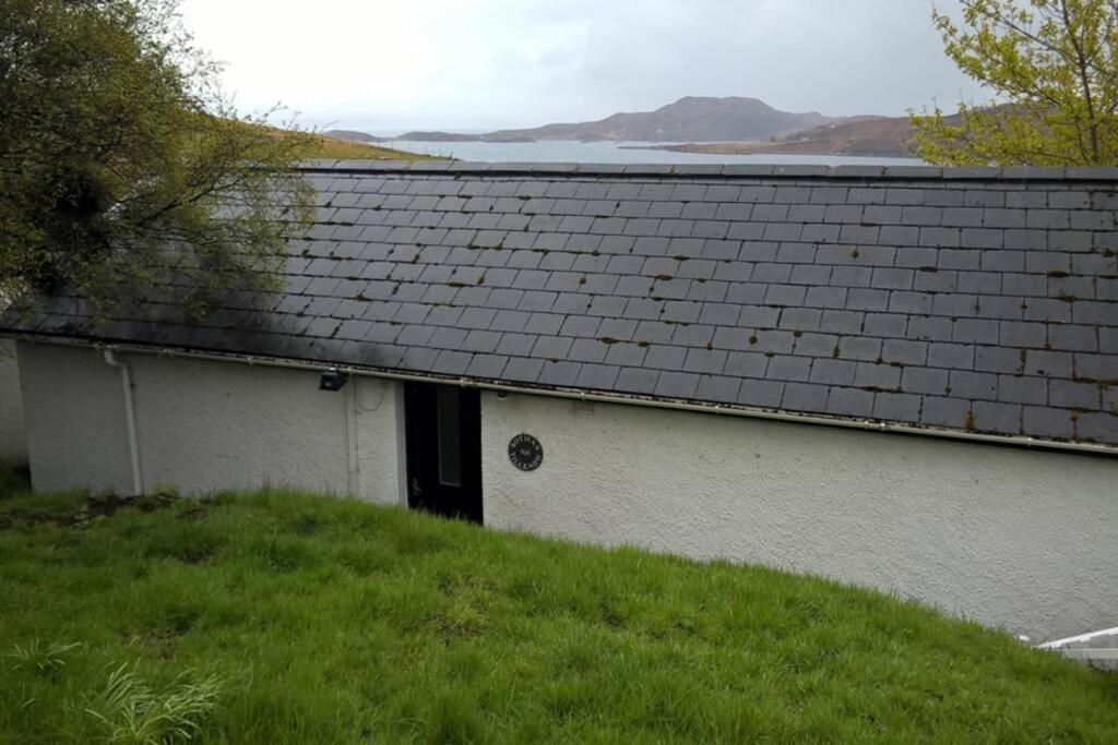 a white house with a black roof on a hill at Bothan na Tilleadh in Achiltibuie