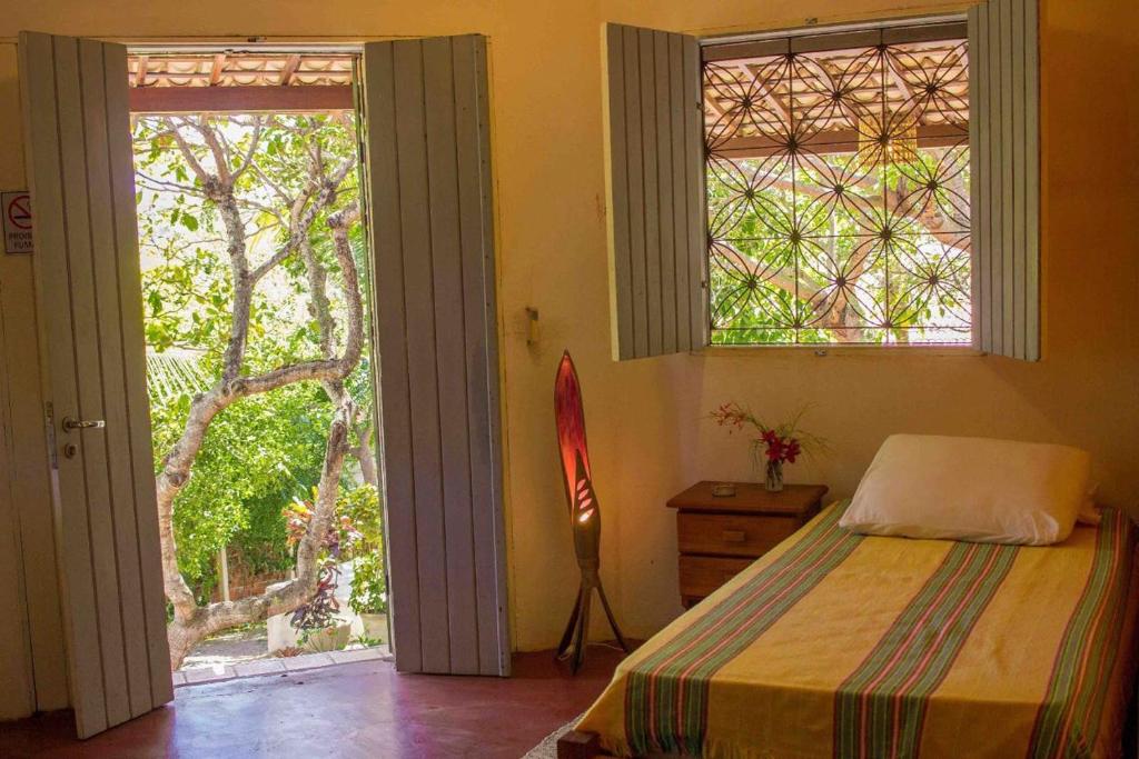 a bedroom with a bed and two windows and a door at Stay Cool Pipa in Pipa