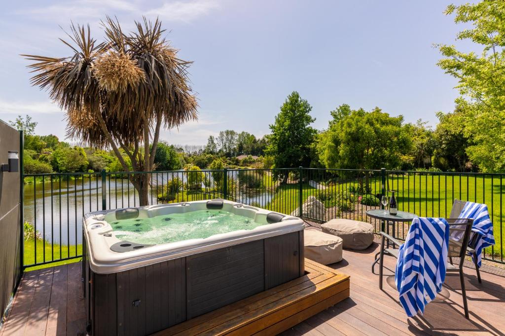 a hot tub on a deck with a table and chairs at Accent House Luxury Boutique Bed & Breakfast in Mapua