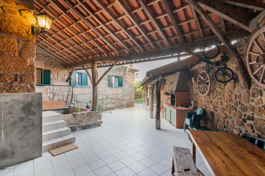 un patio al aire libre con techo de madera y mesa en Casa Outeiro de Cima - Casa Rústica típica Serrana - Seia - SERRA DA ESTRELA, en Seia