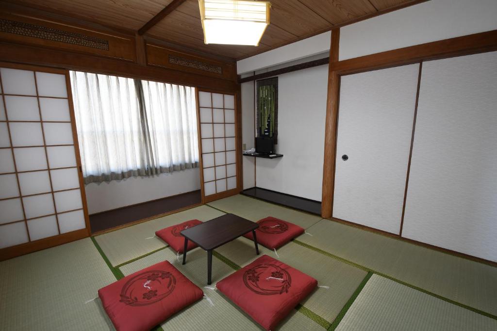 Onsenyado Hamayu Nagi في بيبو: غرفة فارغة فيها كراسي حمراء وطاولة