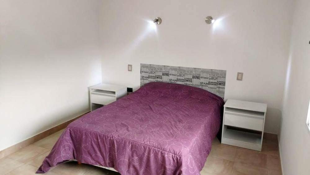 1 dormitorio con 1 cama de color púrpura y 2 mesitas de noche en Depto planta alta en Salta