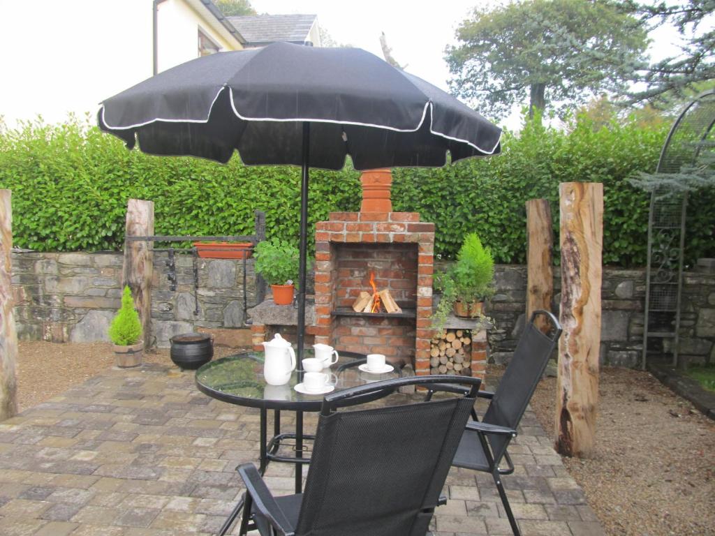 a table with an umbrella and a fireplace at Neidin House in Kenmare