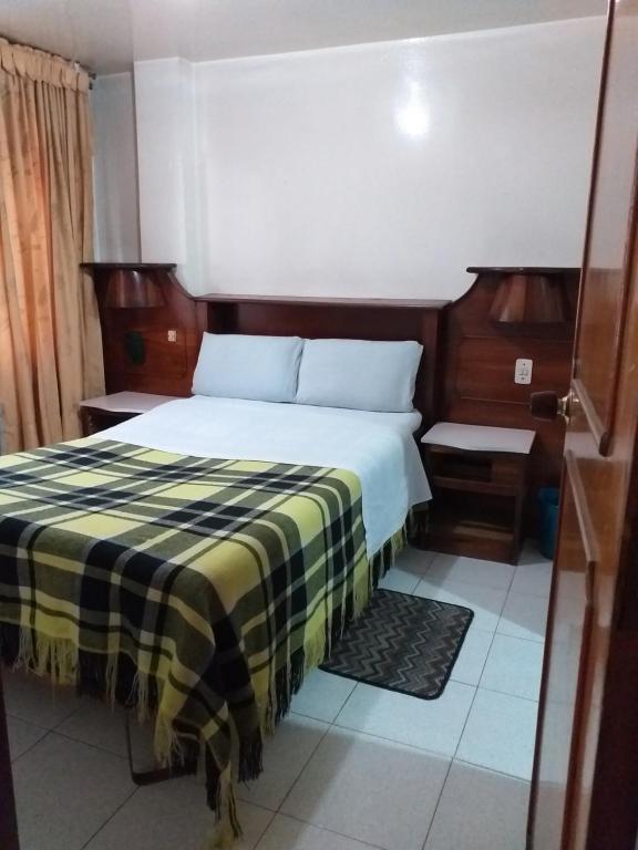 a bedroom with a bed with a checkered blanket at Hotel Plata in Bogot&aacute;