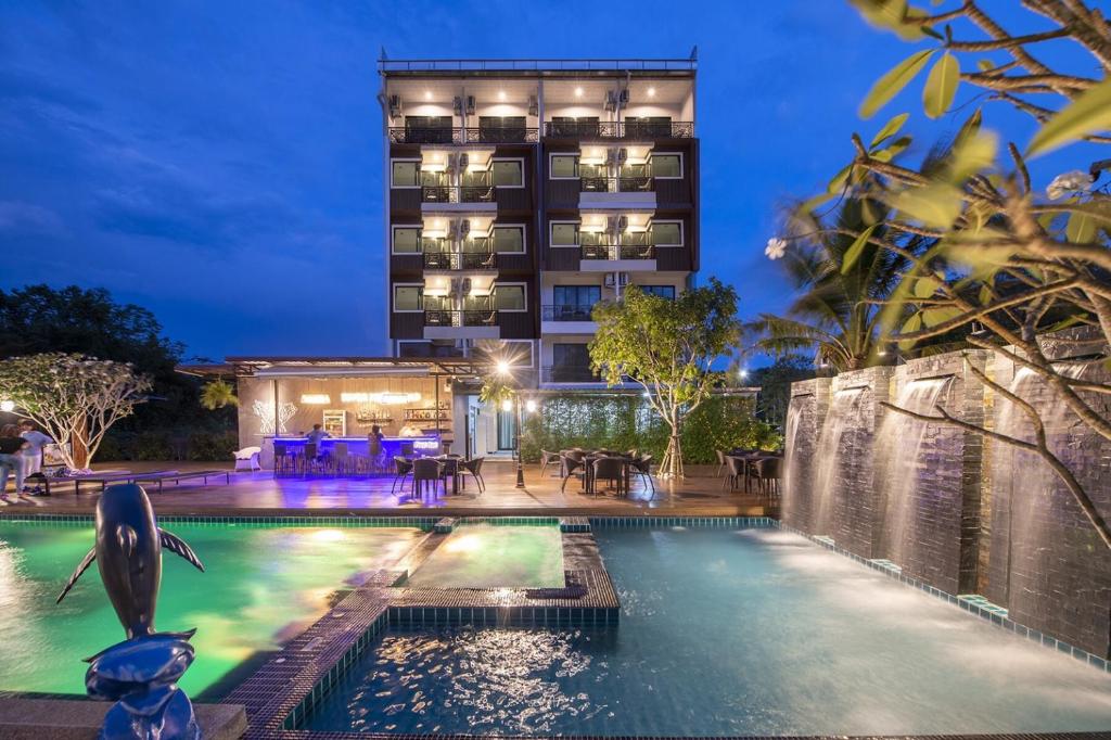a pool at night with a hotel in the background at River Front Krabi Hotel in Krabi