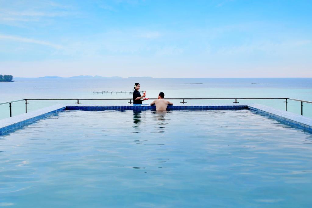 two men standing in a swimming pool in the water at Royal Ocean View Beach Resort in Karimunjawa