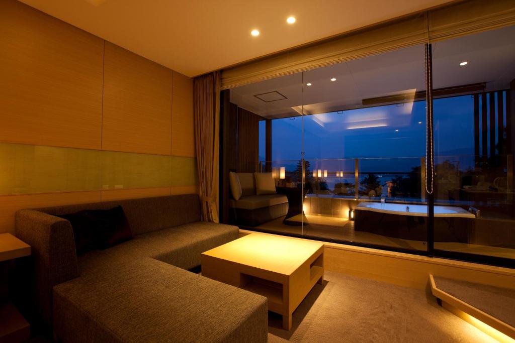 a living room with a couch and a large window at Miyajima Grand Hotel Arimoto in Miyajima