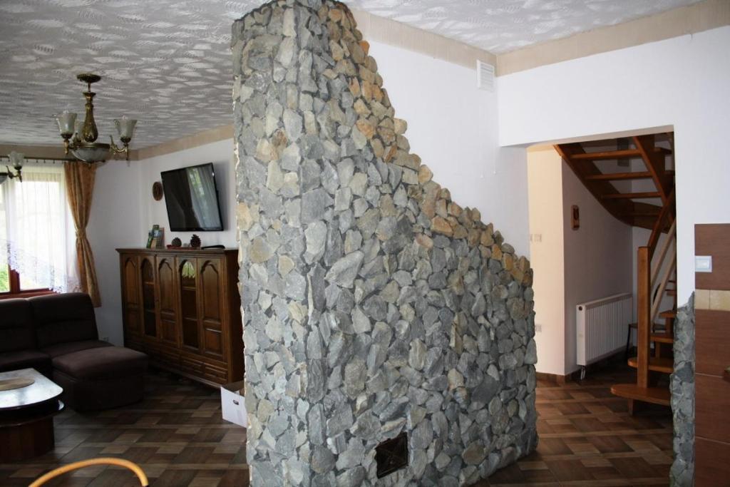 a stone fireplace in the middle of a living room at Dom w Bieszczadach 10 osobowy in Wołkowyja