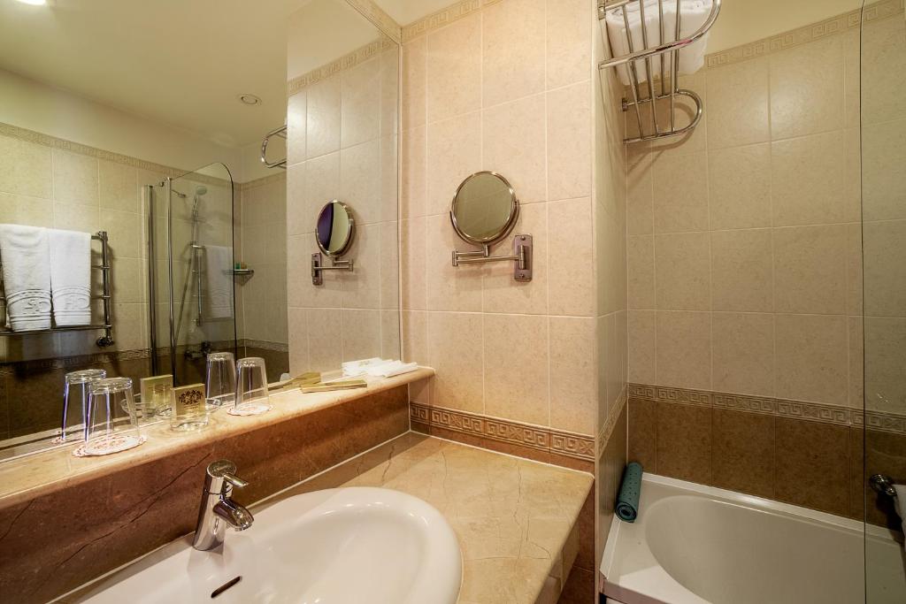 a bathroom with a sink and a tub and a mirror at Kobuleti Georgia Palace Hotel & Spa in Kobuleti