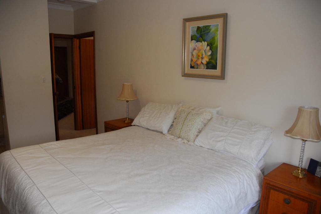 a bedroom with a white bed with two lamps and a picture at Gaerwood B&B in Keith