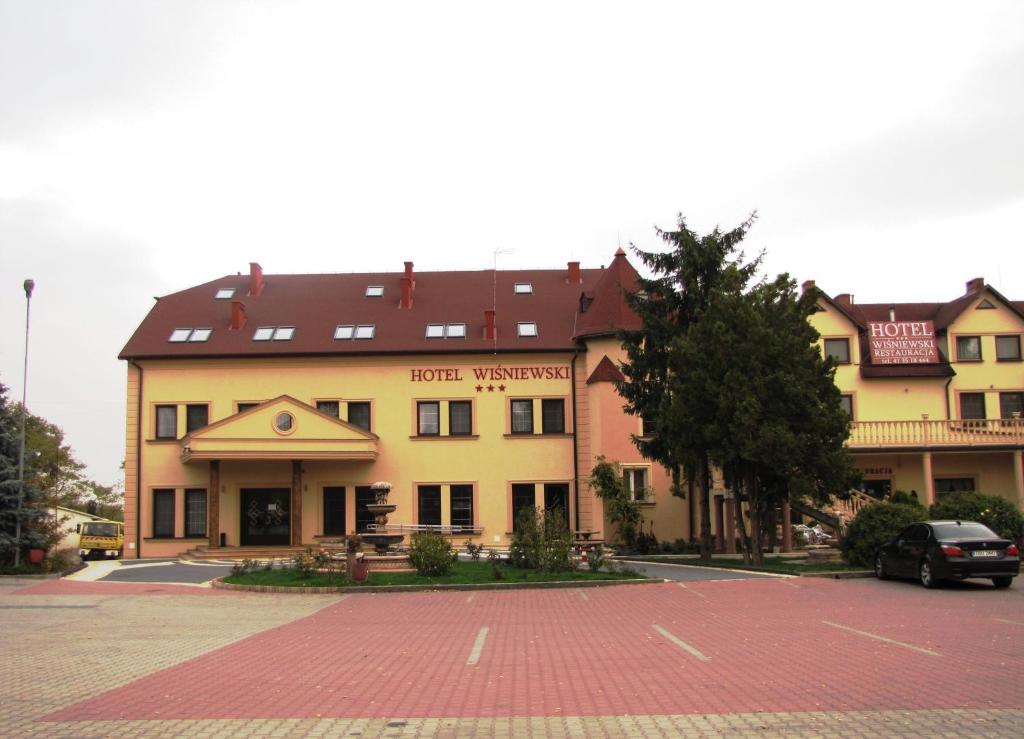 a large building with a parking lot in front of it at Hotel Wiśniewski in Kraśniów