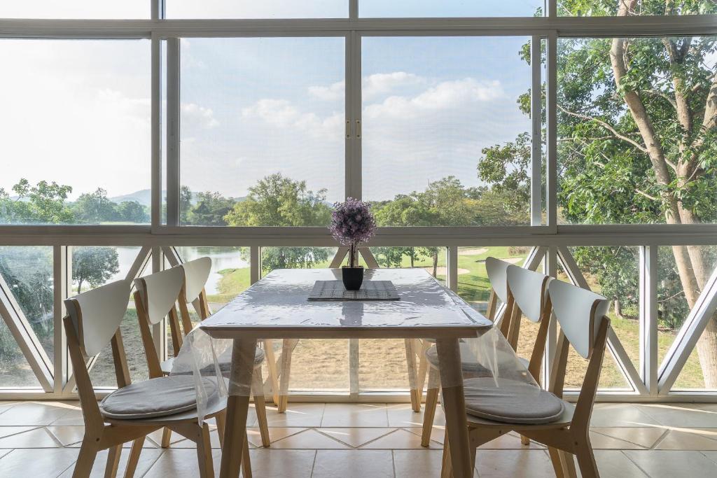 una mesa de comedor con sillas y un jarrón con flores en Golf View Suite Private Apartment Khao Yai en Ban Khanong Phra Klang (1)