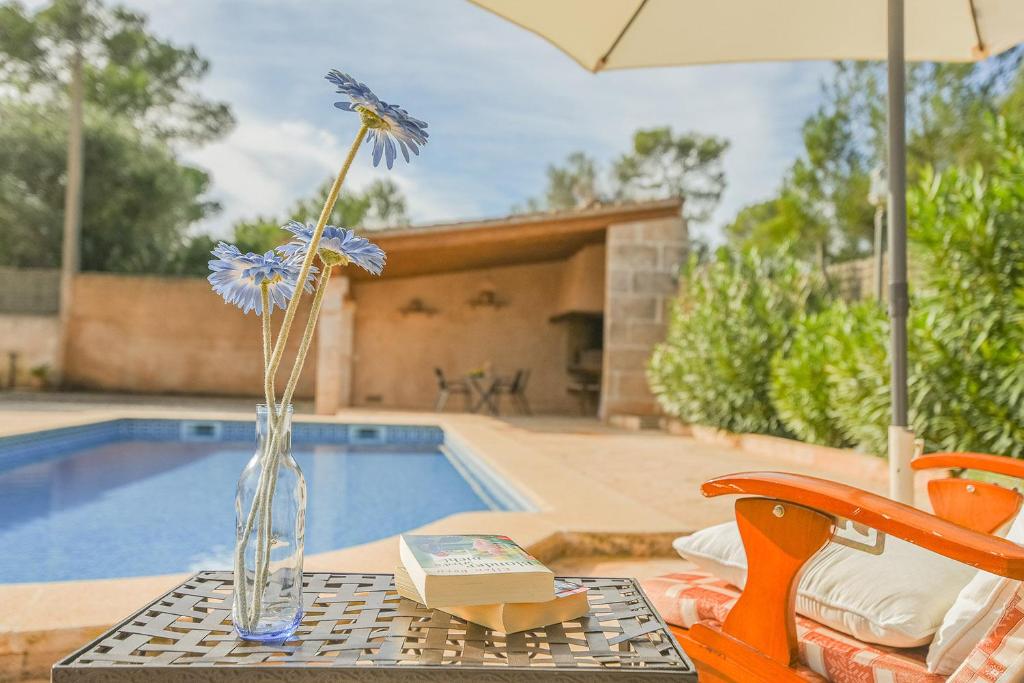 un jarrón con una flor sentado en una mesa junto a una piscina en Mallorcan stone house Villa Matias, en Campos