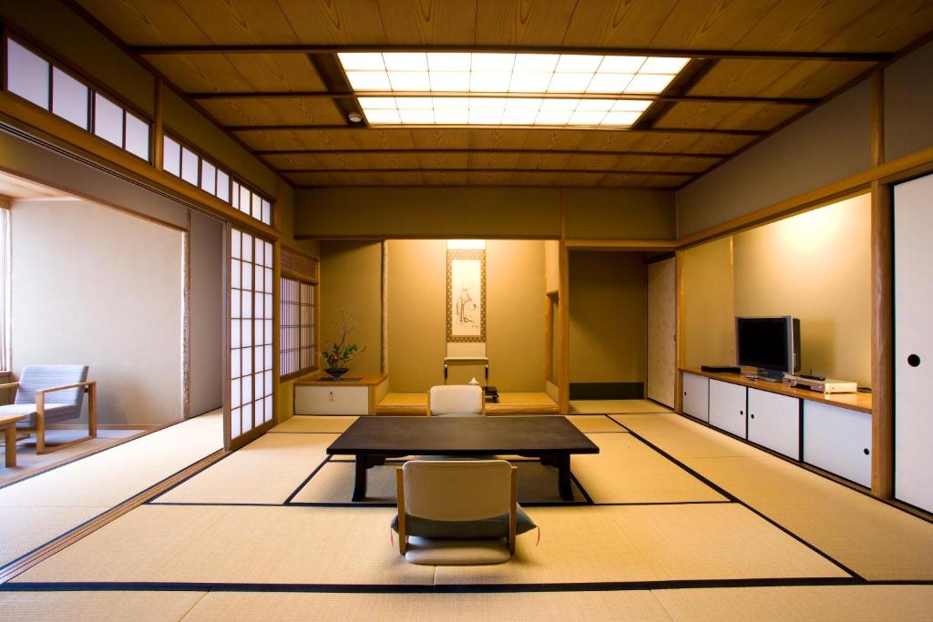 a room with a table and a chair in it at Miyajima Grand Hotel Arimoto in Miyajima