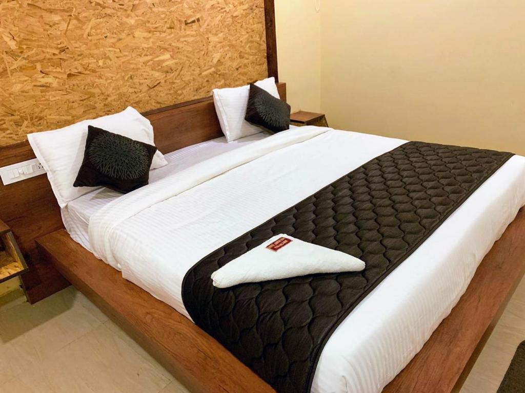 ein großes Bett mit weißer Bettwäsche und schwarzen Kissen in der Unterkunft Hotel Annai Bay in Velankanni