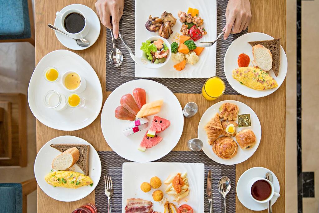 a table with plates of breakfast food on it at Paris Deli Danang Beach Hotel in Danang