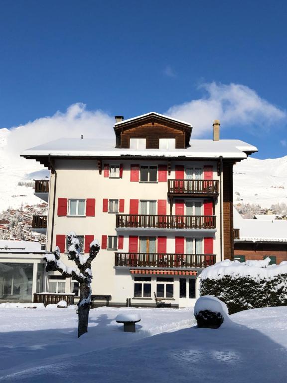 Hotel de la Poste Verbier في فيربير: مبنى بالثلج وامامه شجرة