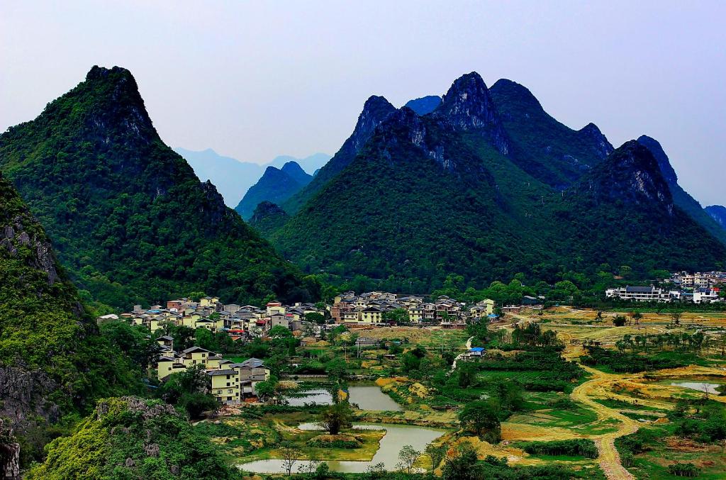 a village in a valley with mountains in the background at Secret Courtyard Resort Hotel in Guilin