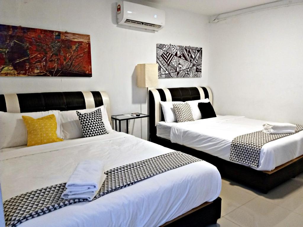 two beds in a room with white walls at Pengkalan Dua in Melaka