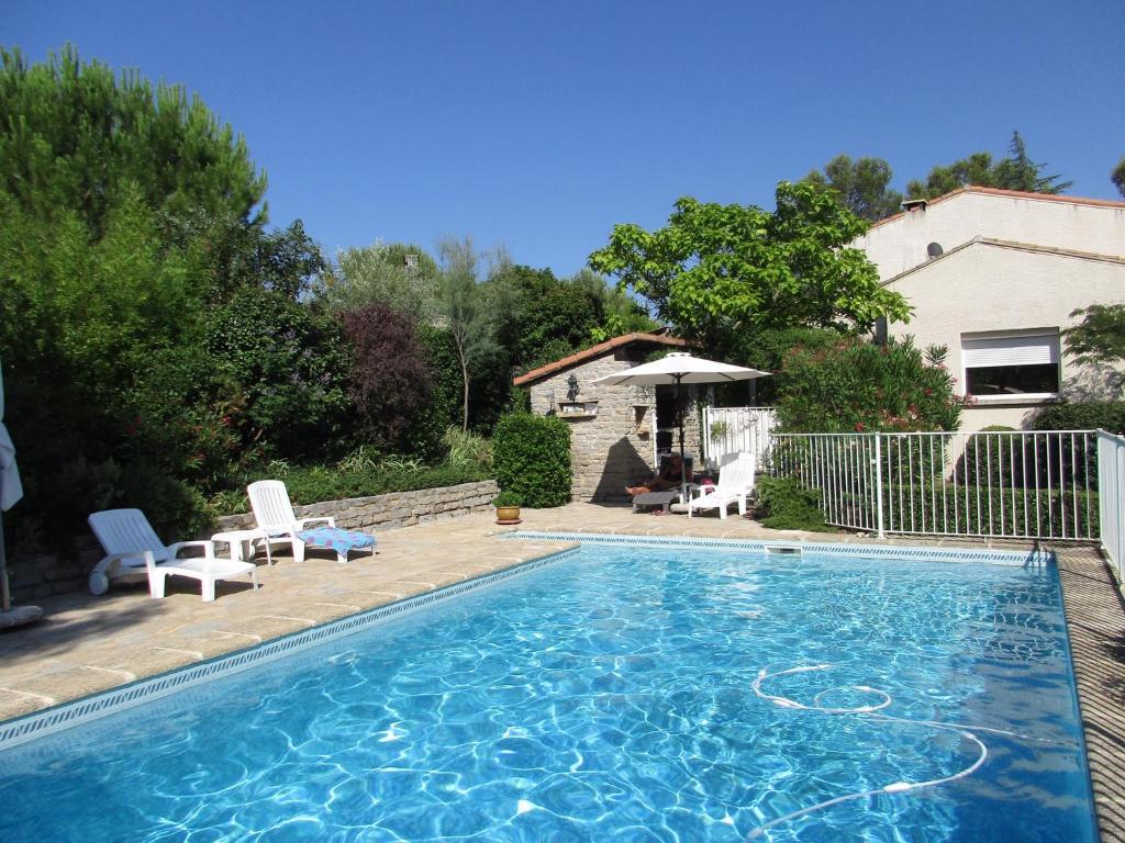 a swimming pool with two chairs and a house at Clos des Cailloux in Prades-le-Lez