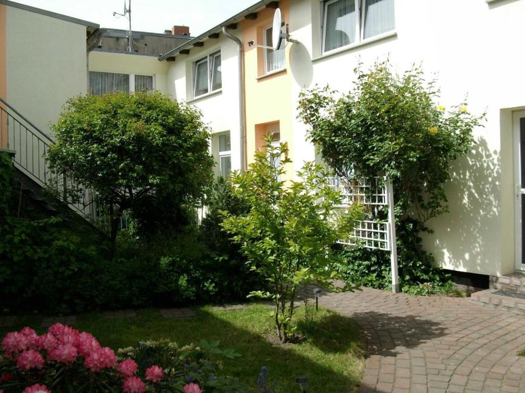 einen Garten vor einem Gebäude mit Bäumen und Blumen in der Unterkunft Appartement Feuerdorn in Warnemünde