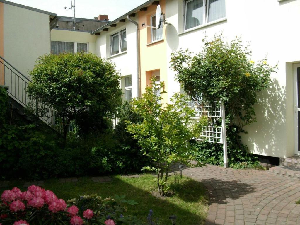 a garden in front of a building with trees and flowers at Appartement Feuerdorn in Warnemünde