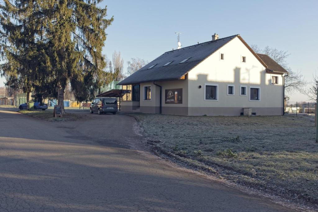 une maison blanche avec une voiture garée devant elle dans l'établissement Penzion&Pizzerie U Massima, à Vyškov
