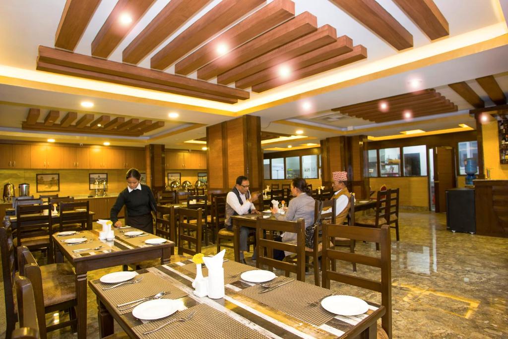 ein Restaurant mit Holztischen und Menschen, die darauf sitzen in der Unterkunft Hotel Yellow Pagoda Pokhara in Pokhara