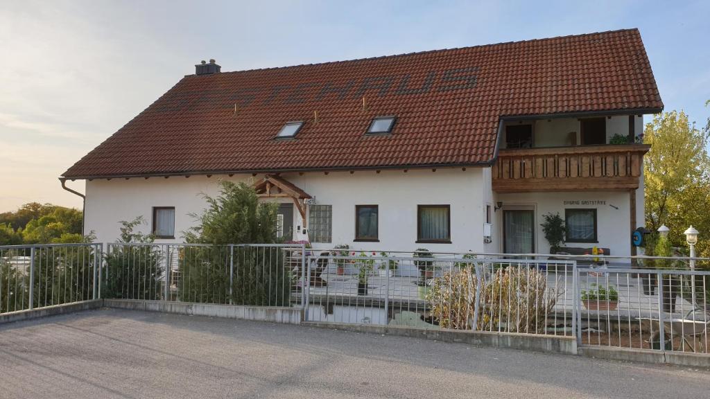 ein weißes Haus mit einem braunen Dach und einem Zaun in der Unterkunft Mainstern Hotel in Schonungen