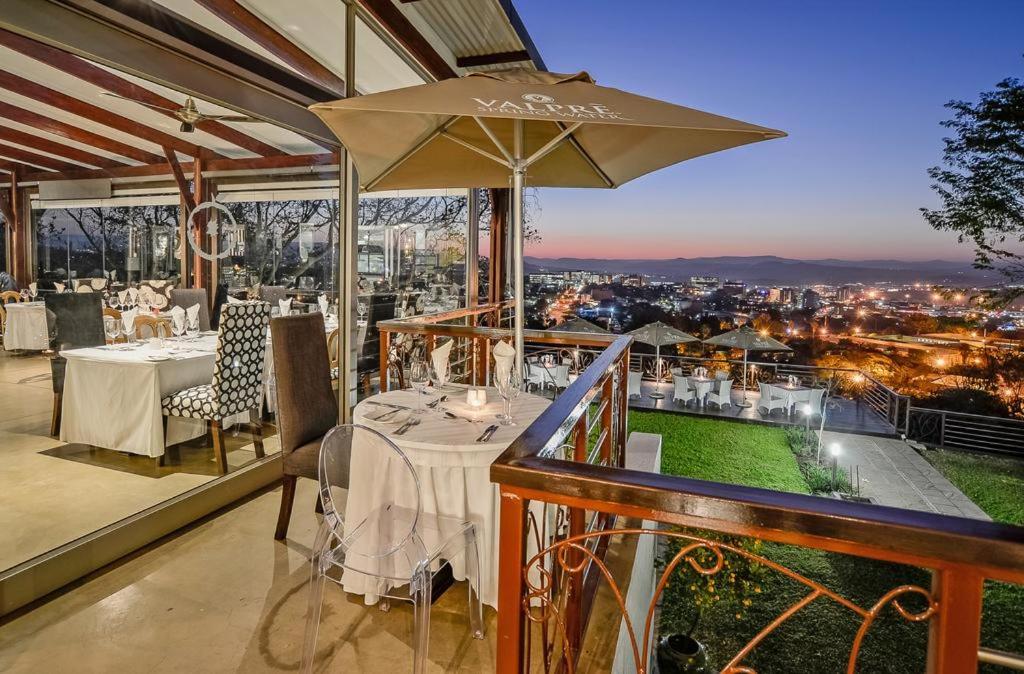 a restaurant with a table and an umbrella on a balcony at Francolin Lodge in Nelspruit