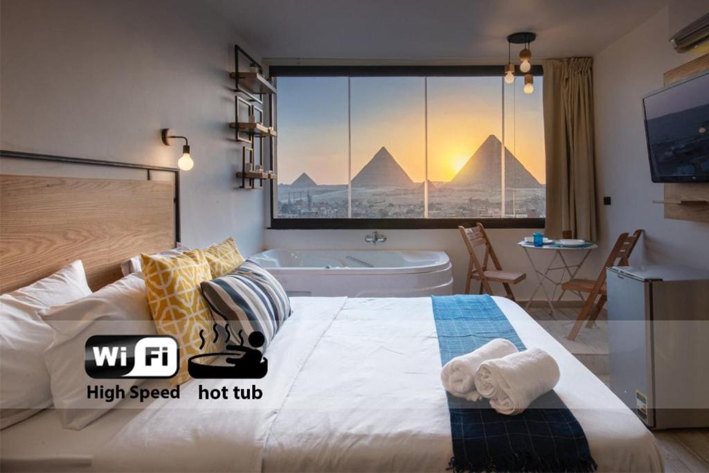 um quarto com uma cama grande e vista para as pirâmides em Jacuzzi By The Historic Giza Pyramids - Apartment 3 no Cairo