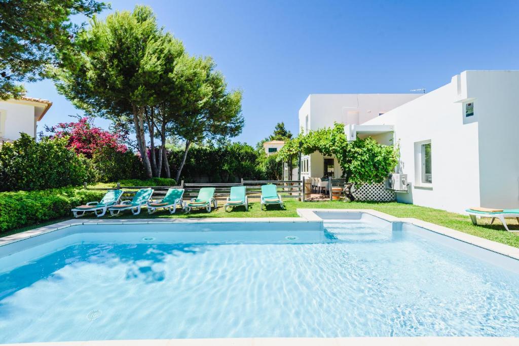 een zwembad met stoelen en een huis bij Villa 715 - our Albufeira holiday retreat in Albufeira
