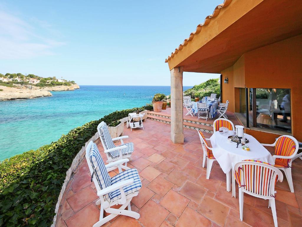 a patio with white tables and chairs and the ocean at Holiday Home Cala Mendia Sea Views by Interhome in Porto Cristo