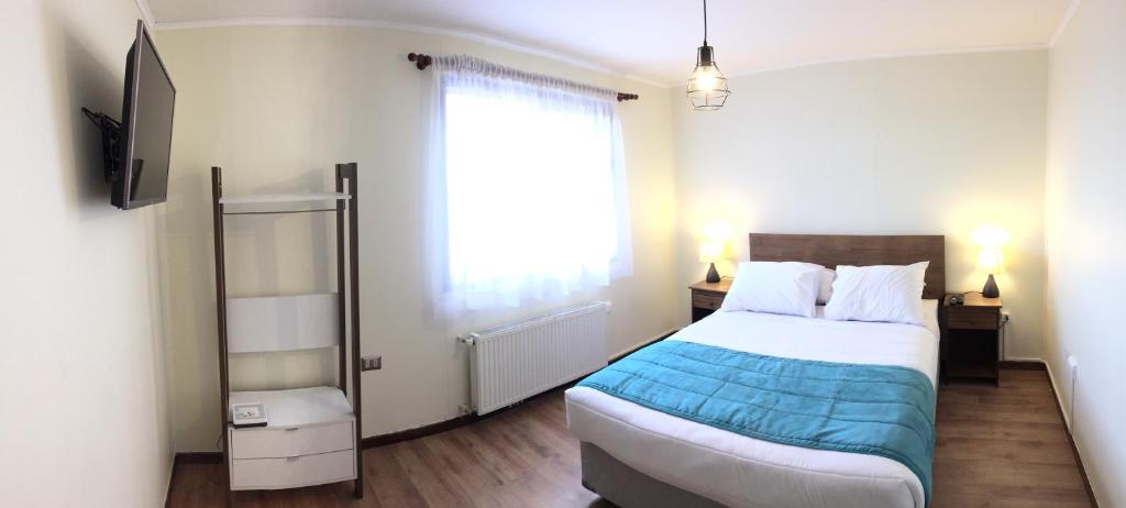 a bedroom with a large bed and a window at Haiken Hostal in Punta Arenas