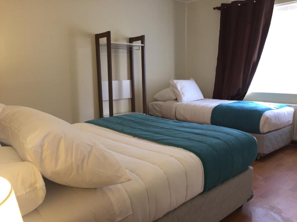 a room with two beds and a couch at Haiken Hostal in Punta Arenas
