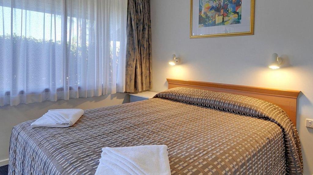 a bedroom with a bed with two towels on it at Cedar Lodge Motel in Morwell