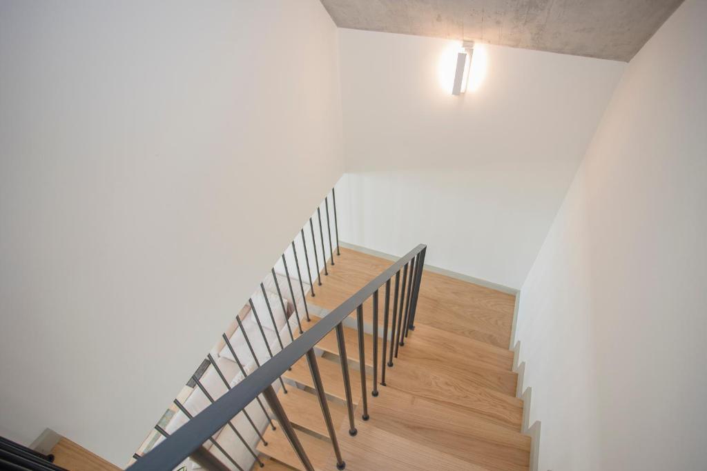 a staircase with wooden floors and a white wall at Liiiving in Porto - Luxury Beachfront Apartments in Porto