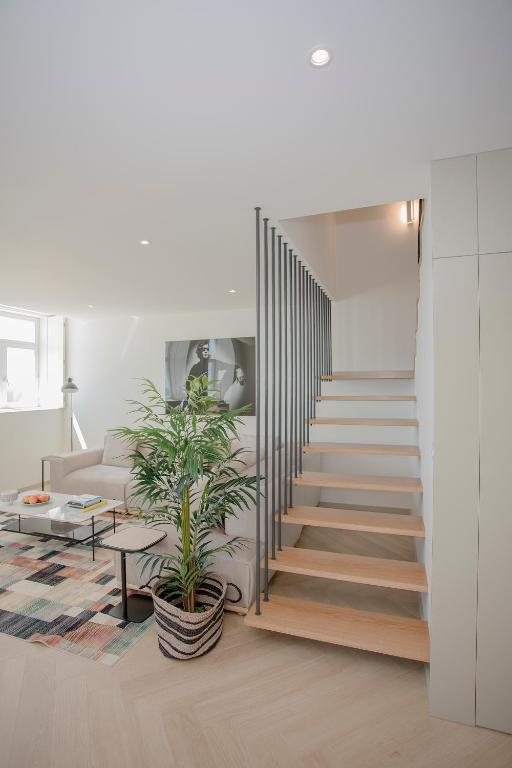 a staircase in a living room with a plant at Liiiving in Porto - Luxury Beachfront Apartments in Porto